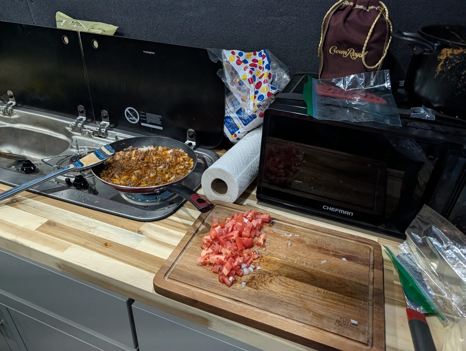 Real camp food preparation inside Chris Follin's van with a stove, pan, cutting board, and ingredients